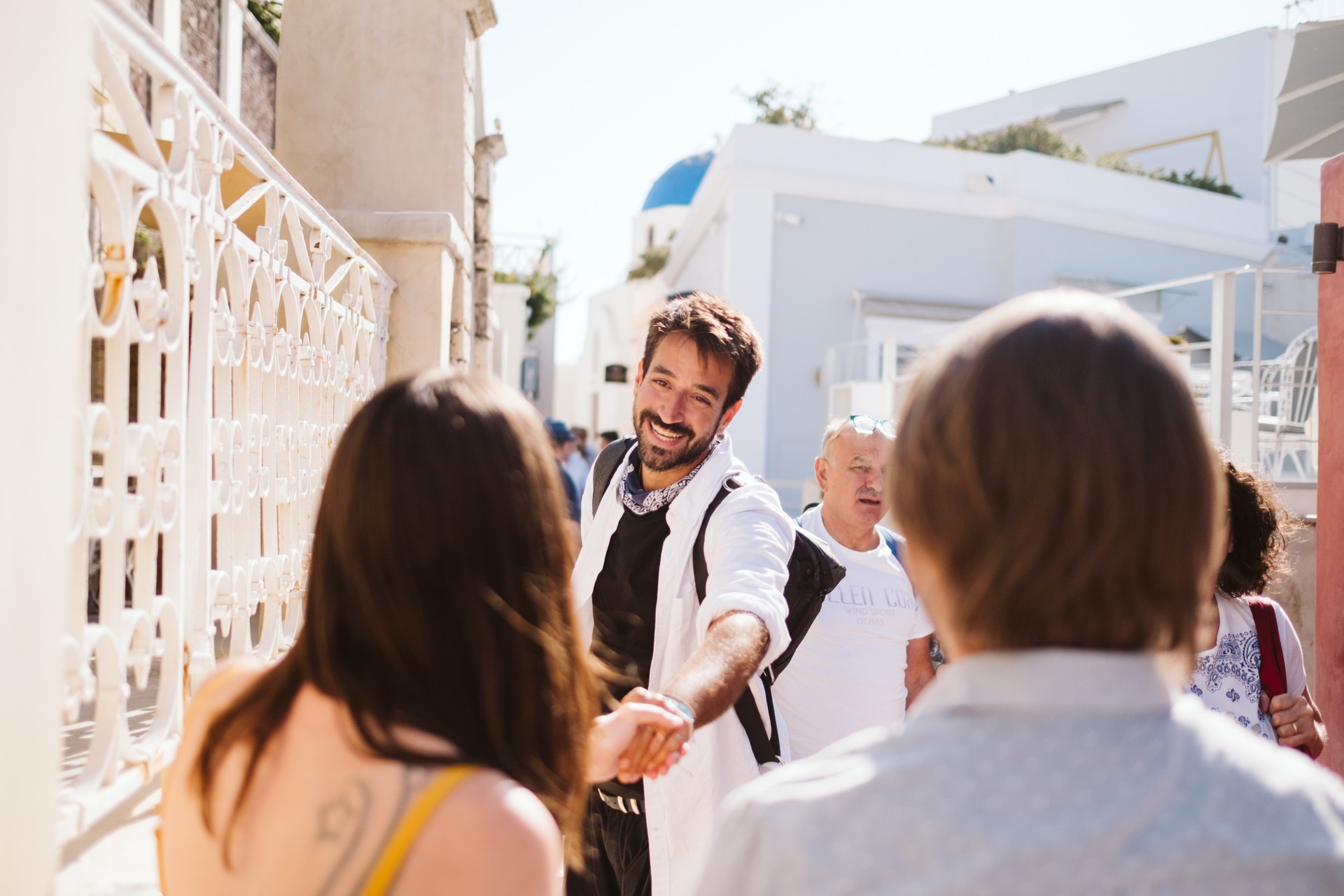 A smiling photographer meets his couple clients to start their Flytographer shoot in Santorini